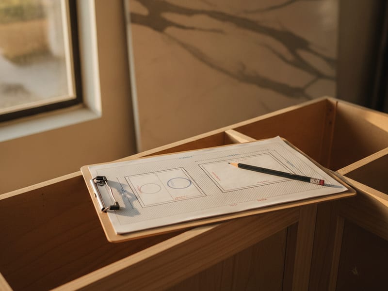 Homeowner measuring kitchen cabinet depth with a tape measure in a San Diego home